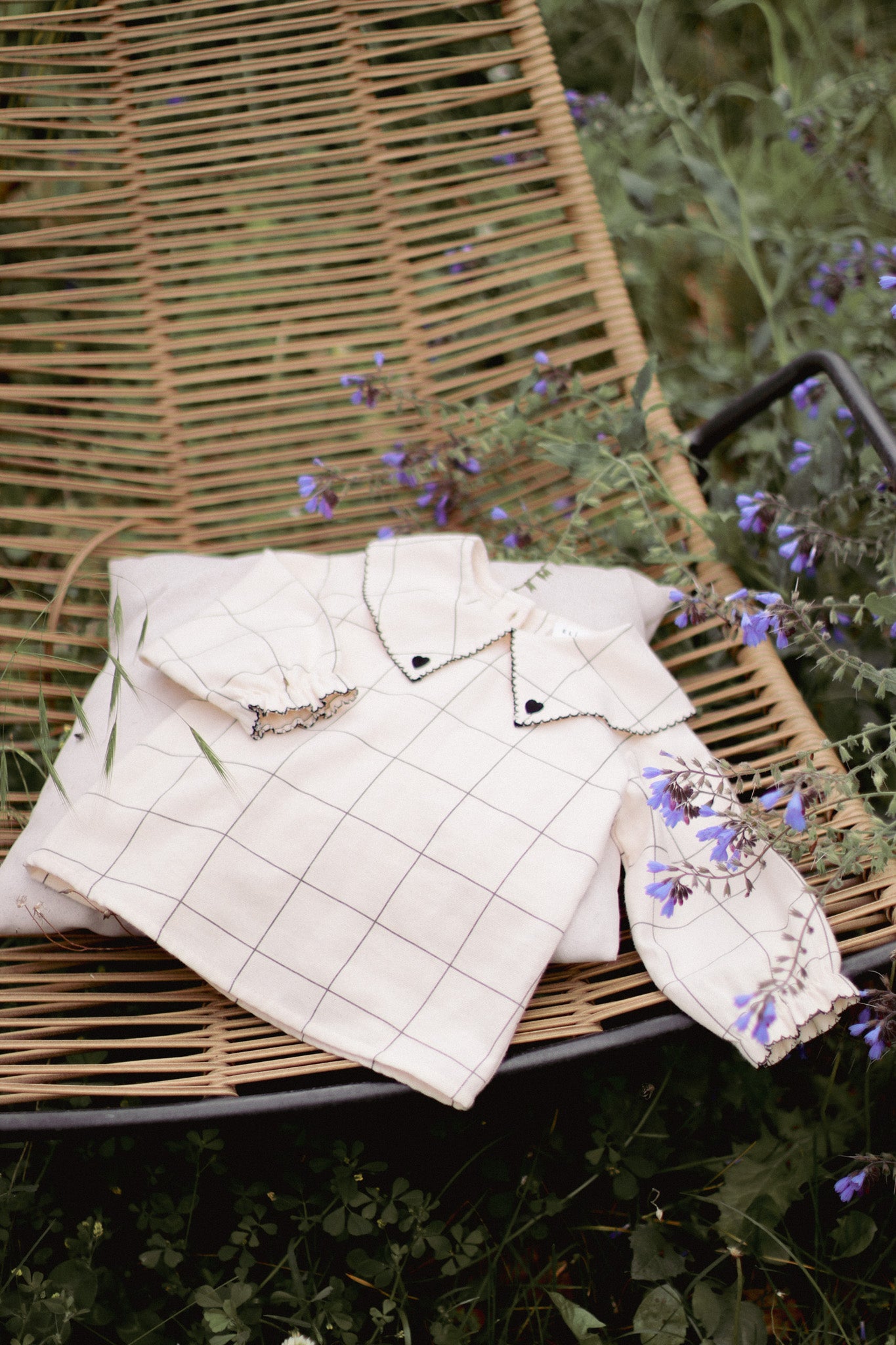 Shop the DALILA Blouse by Eli & Nev — a baby and toddler blouse in 100% OEKO-TEX certified cotton. Designed with a faded black check on beige, black trim with heart embroidery, elastic cuffed sleeves, and coconut button closure. Ethically made in Turkey, perfect for stylish and comfortable everyday wear. European baby clothing gift
